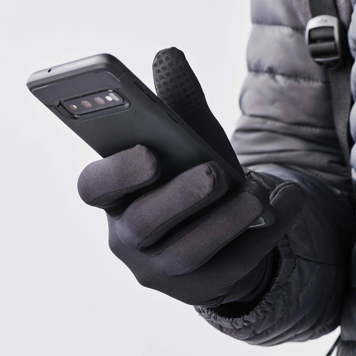 Person wearing black gloves using a smartphone.
