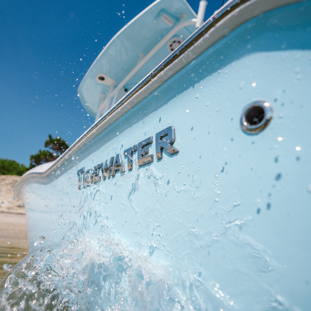Close-up of a light blue boat with the word 'TIDEWATER' on the side, with splashing water in the foreground.