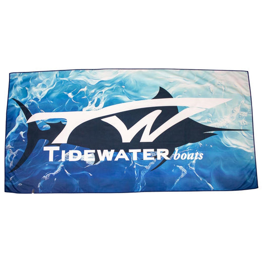 Microfiber beach towel with a blue wave design, a dark blue fish silhouette, and the tidewater logo in white. 